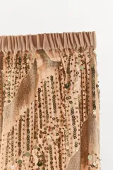 Pantalón de tiro medio con cintura elástica y bajo abullonado. Presenta un diseño con hilo metalizado y aplicaciones de abalorios y lentejuelas en toda la prenda.