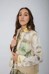 Chaqueta color beige con estampado abstracto en tonos amarillos, con cuello camisero, cierre frontal con botones, bolsillos plaqué y puños camiseros.