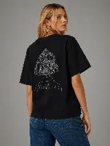 Remera negra de algodón con silueta boxy y mangas cortas. En la espalda presenta un diseño estampado de líneas blancas que ilustra una cabeza de espaldas con cabello recogido y la palabra 'Whatever'.