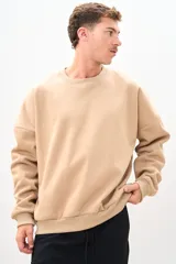 Buzo color beige de corte holgado, con cuello redondo y mangas largas.