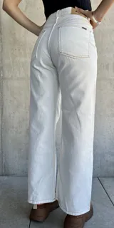 Pantalón jean de tiro alto color blanco, corte recto y pierna ancha.
