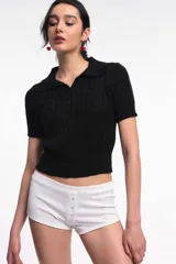 Top de tejido de punto negro con diseño texturizado, cuello polo y mangas cortas.