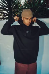 Hoodie negro con capucha, de corte holgado, que presenta un diseño gráfico grande en color blanco en la espalda y un detalle estampado en la manga.