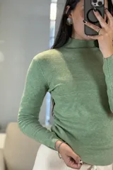 Buzo de tejido de punto fino en color verde, con cuello medio y mangas largas, de corte ajustado al cuerpo.
