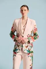 Saco de mujer Natalia Antolin con silueta estructurada, solapa chal y un llamativo estampado floral y botánico en tonos verdes, rojos y blancos sobre base rosada.