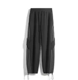 Pantalón deportivo negro de corte ancho y tiro alto con cordón ajustable en la cintura. Presenta tres franjas verticales grises oscuras en los laterales y un bolsillo cargo con solapa en el muslo derecho. Los tobillos son ajustables.