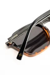 Lentes de sol polarizados con armazón negro de diseño geométrico y lentes oscuros.