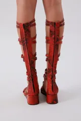 Sandalias gladiadoras rojas con estampado de piel de serpiente, tiras finas y cierre con cordones.