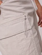 Bermuda cargo de corte recto, color beige, con cintura elástica y cordón de ajuste. Presenta bolsillos laterales con solapa y cierre, confeccionada en tejido de algodón con elastano.