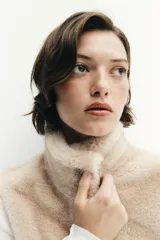 Chaleco de efecto pelo con cuello subido, diseño sin mangas y cierre frontal con cremallera metálica.