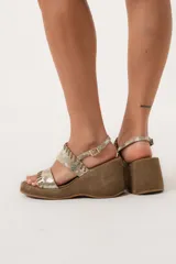 Sandalias de cuero color dorado con plataforma y taco de cuña forrado en gamuza marrón.