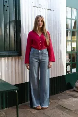 Pantalón de denim tiro alto con corte wide leg, lavado medio con desgastado suave, costuras clásicas y terminación en ruedo deshilachado. Diseño de panel lateral en tono más oscuro.
