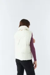 Chaleco blanco con cuello alto y bolsillos laterales.