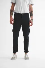 Pantalón cargo negro de gabardina con puños elásticos en los tobillos y múltiples bolsillos.