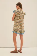 Vestido corto de algodón con estampado floral en tonos amarillos y azules. Presenta un diseño con volados en las mangas y en el ruedo, con detalles de ribetes en color azul y una textura con hilos metalizados.