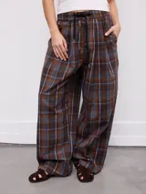 Pantalón de corte ancho y relajado, con estampa a cuadros en tonos marrones y azules. Cuenta con cintura elástica con cordón de ajuste y bolsillos laterales.