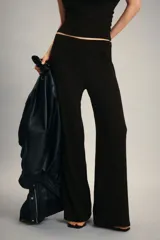 Pantalón de punto color negro con efecto arrugado, tiro alto, cintura elástica y piernas amplias.