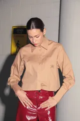 Camisa color camel de poplin de algodón, manga larga y largo a la cintura. Tiene un bolsillo bordado con el isologo de Renée a tono.