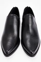 Zapato tipo mocasín de cuero vacuno con textura grabada, diseño de punta fina y taco bajo cuadrado. Cuenta con cierre en la parte posterior del talón.