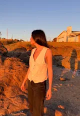 Chaleco de lino en color beige, con escote en V, cierre frontal con botones y bolsillos delanteros decorativos.