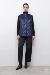 Chaleco capitoneado reversible con cuello alto y cierre frontal con botones a presión. Presenta un diseño acolchado con costuras en forma de rombos.