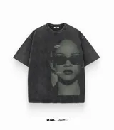 Remera oversize de algodón, color gris oscuro con efecto stone wash. Presenta un estampado frontal en tonos oscuros de la cantante Rihanna usando gafas de sol.
