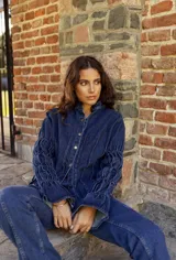 Camisa de jean azul oscuro con cuello mao, cierre frontal con botones metálicos y mangas largas con detalle de frunces elásticos.