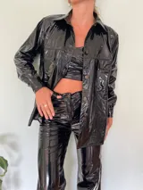 Camisa negra de charol con cuello clásico, cierre frontal con botones y bolsillos de parche en el pecho.