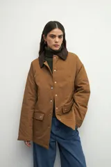 Campera color verde militar con cuello de pana marrón, bolsillos con solapa y botones metálicos. Interior forrado con tela satinada capitoneada.