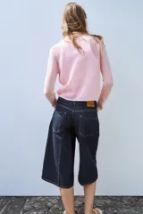 Chaqueta de punto color rosado con cuello polo, manga larga y cierre frontal con botones.