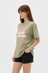 Remera de algodón color beige con estampado frontal de un corazón rosado que contiene un moño. Tiene cuello redondo y mangas cortas.