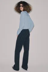 Jeans de tiro alto con corte flare y diseño de rayas verticales. Presenta cintura con trabillas, falsos bolsillos delanteros con solapa y botón, y cierre frontal con cremallera y botón.