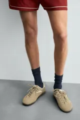 Zapatilla de cordones de estilo retro, con parte superior de serraje color bordó y detalles en piel lisa color rojo. Suela ultrafina de goma en tono marrón oscuro.