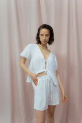 Short blanco de calce relajado con cintura elástica y lazo regulable. Presenta bolsillos amplios con ribete interior de color naranja neón.