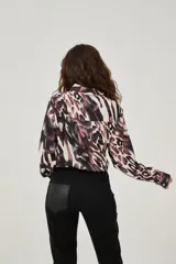 Camisa de manga larga con estampado abstracto en tonos marrones y blancos, cuello camisero y cierre frontal con botones. Puños con detalle de estampado animal print.