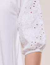 Blusa Liv Los Angeles de color blanco, confeccionada con torso de modal y mangas tres cuartos con detalles de bordado calado. Presenta cuello redondo con apertura central y cierre frontal de botones.