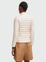 Chaqueta corta acolchada de Moncler, color rosa pálido, con cuello alto, cierre frontal con cremallera y diseño de líneas horizontales.
