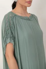 Vestido largo de seda color verde seco, con transparencias en el ruedo, mangas cortas y detalle de guarda bordada con lentejuelas en hombros y mangas.