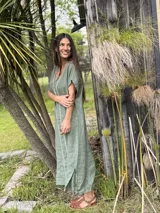 Vestido largo verde militar de lino, con cuello en V, mangas cortas y detalle de bordado blanco geométrico en el centro y escote. Presenta aberturas laterales en el ruedo.