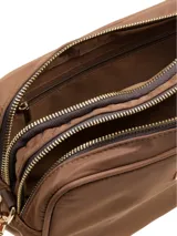 Cartera bandolera color marrón chocolate, con correa de tela a rayas marrones y beige, y logo metálico en el frente.