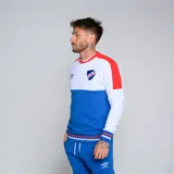 Buzo de cuello redondo Umbro del Club Nacional de Football. Diseño tricolor con cuerpo superior blanco, franja central azul y detalles en rojo en hombros y puños. Incluye logo de Umbro y escudo del club en el pecho.