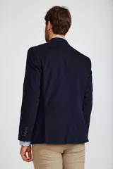 Blazer de pana color marrón oscuro, con cierre frontal de dos botones, solapas clásicas y bolsillos laterales con solapa. Presenta un diseño estructurado y elegante.