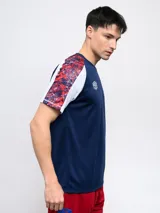 Remera de fútbol Umbro del Club Nacional de Football, modelo Pro Training Active. Diseño con estampado abstracto en blanco, rojo y azul, con mangas raglán azul marino y escudo del club en el pecho.