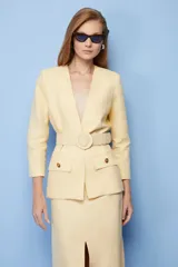 Blazer amarillo con solapas, corte entallado, cierre cruzado con botón y cinturón con hebilla redonda.