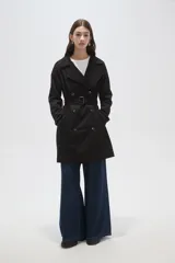 Trinchera de corte clásico, color negro, con cierre frontal de doble botonadura, solapas amplias y cinturón ajustable con hebilla en la cintura.