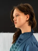 Blusa azul de algodón tipo seda, teñida a mano con técnica tie dye. Tiene corte recto, mangas cortas abullonadas con elástico y cierre invisible en el escote delantero.