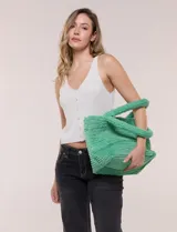 Cartera tipo shopper verde de textura suave y flexible, con doble asa superior fija texturada y compartimento principal amplio con botón metálico.
