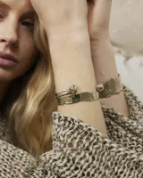 Pulsera esclava abierta de diseño orgánico con terminaciones redondeadas, realizada en metal con acabado texturizado.