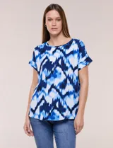 Blusa de silueta holgada y recta, confeccionada en crepe de poliéster con estampado animal print. Presenta escote redondo clásico, mangas cortas de hombro caído con puño doblado y ruedo ligeramente curvo.