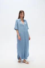 Vestido largo tipo camisero de lyocell, con cuello camisero, cierre frontal de botones, mangas cortas con dobladillo y bolsillos laterales. Presenta un corte holgado y tajos laterales en el ruedo.